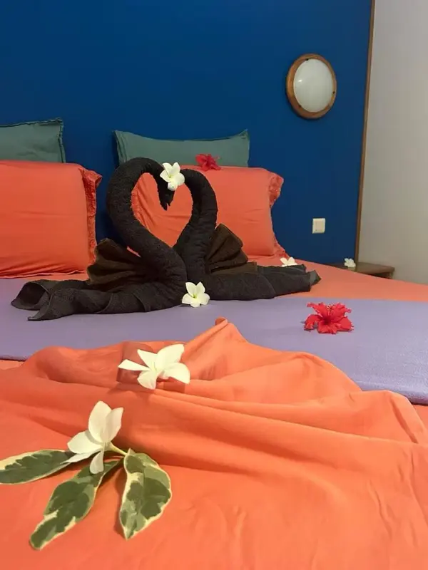 Un lit double est décoré de serviettes en forme de cœur et de fleurs.