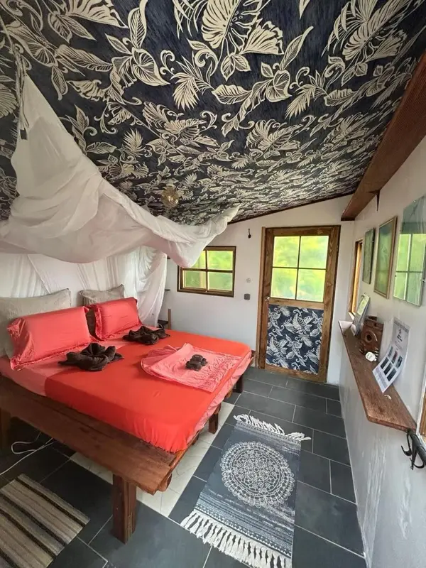 Une chambre à coucher lumineuse avec un lit recouvert d'un tissu rouge vif.