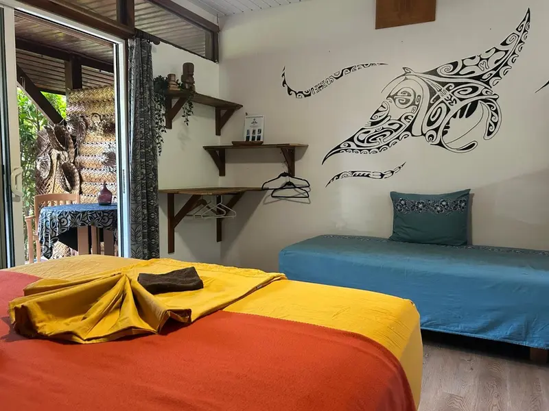 Une chambre lumineuse avec deux lits et une décoration murale tropicale.