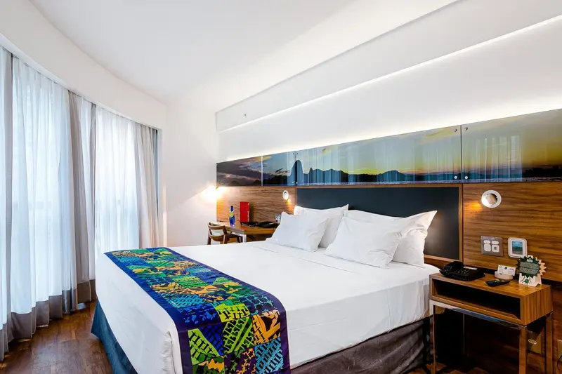 Une chambre lumineuse avec un grand lit recouvert d'une courtepointe colorée.