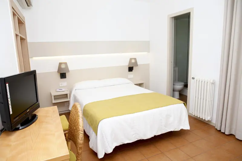 Une chambre lumineuse avec un lit simple et une télévision.
