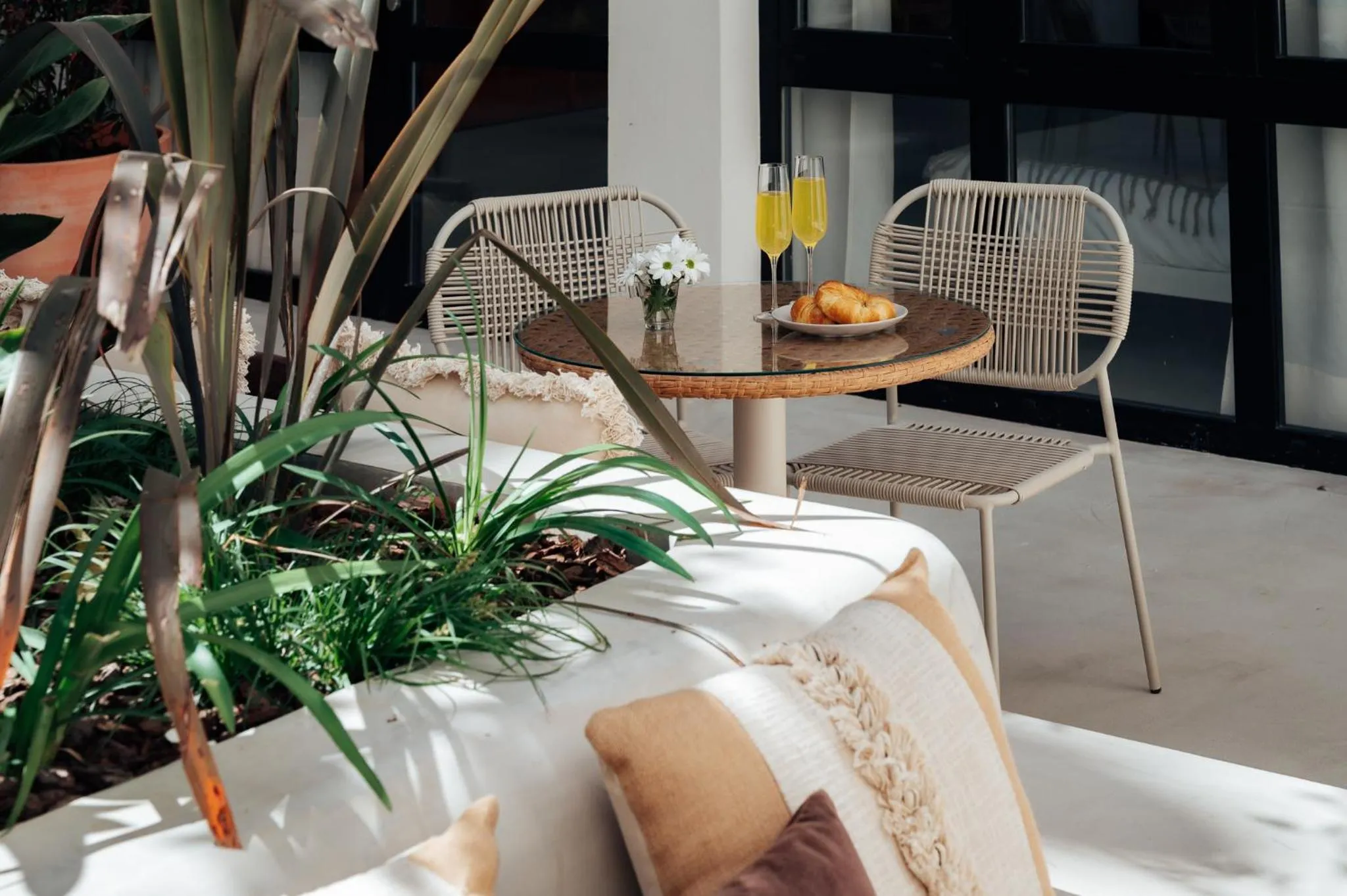 Une table ronde avec des viennoiseries et des boissons est mise en scène sur une terrasse.