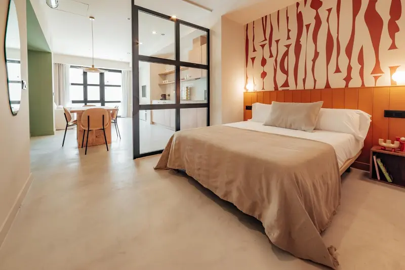 Une chambre lumineuse avec un lit double et un espace repas attenant.