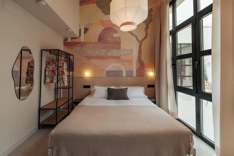 Chambre lumineuse avec un grand lit et une décoration murale abstraite.