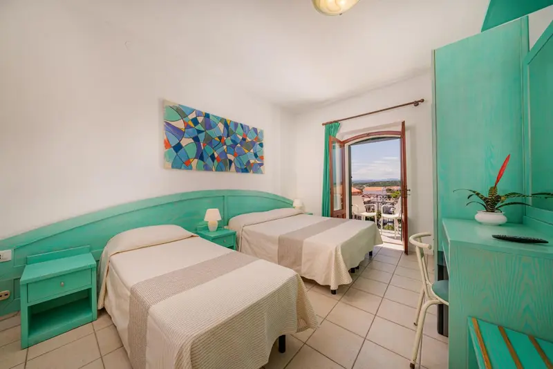 Chambre lumineuse avec deux lits simples et vue sur la mer.