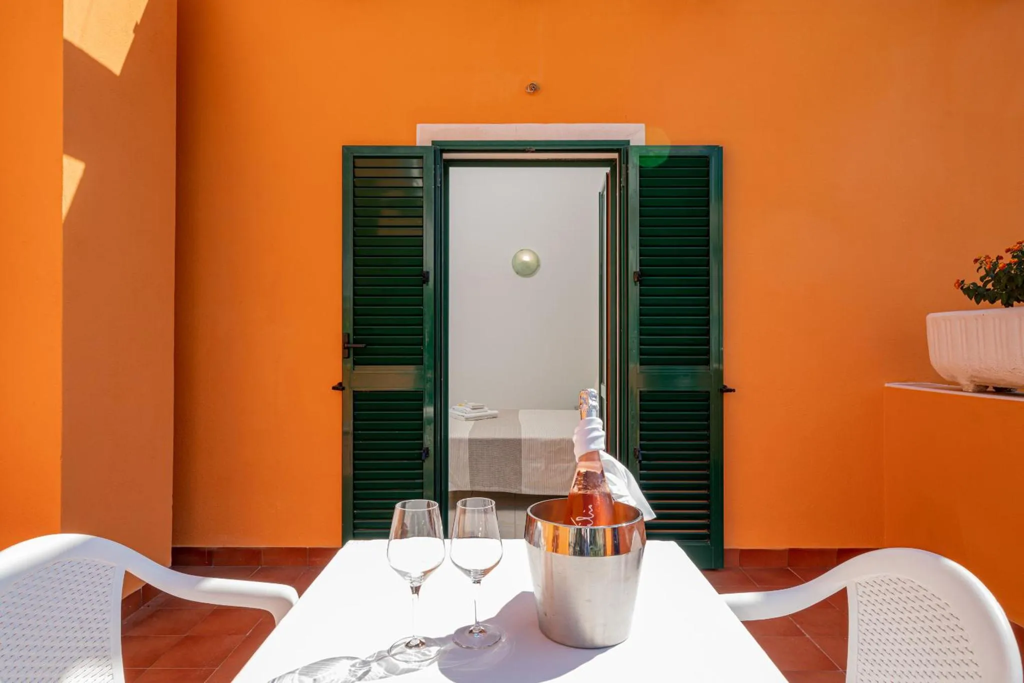 Une table avec des verres et une bouteille sur une terrasse ensoleillée.
