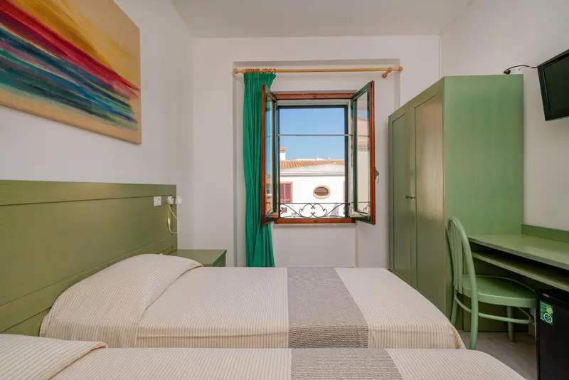 Une chambre lumineuse avec un lit et un bureau près d'une fenêtre.
