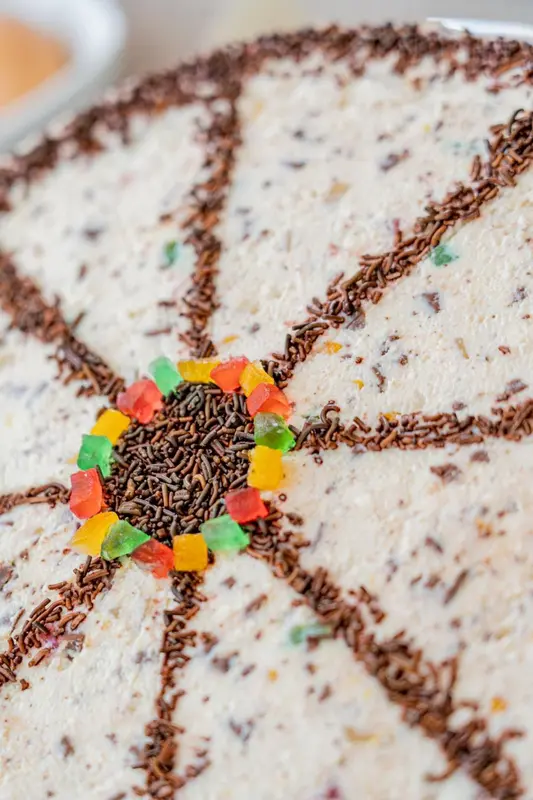 Gros plan d'un dessert rond décoré de chocolat et de vermicelles colorés.