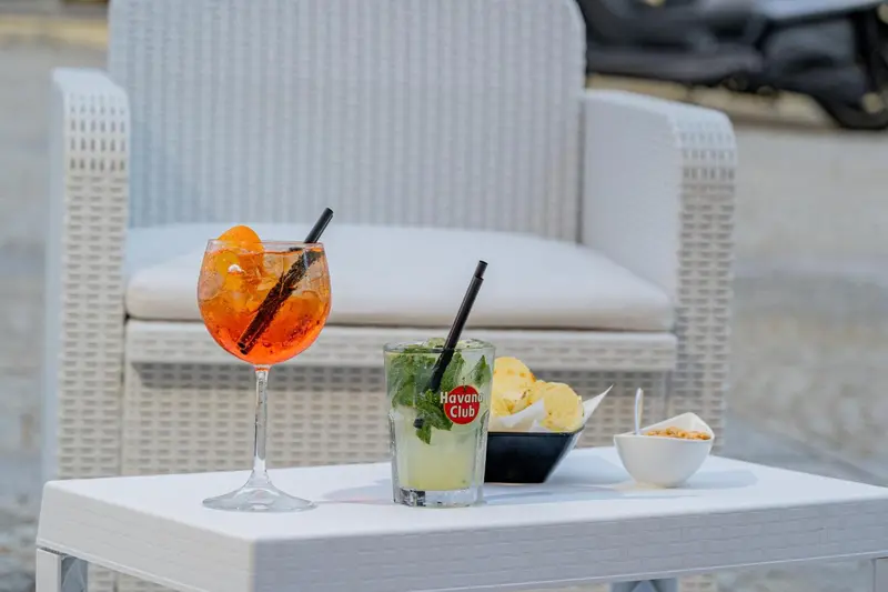 Deux cocktails colorés et des amuse-gueules sont posés sur une table blanche.