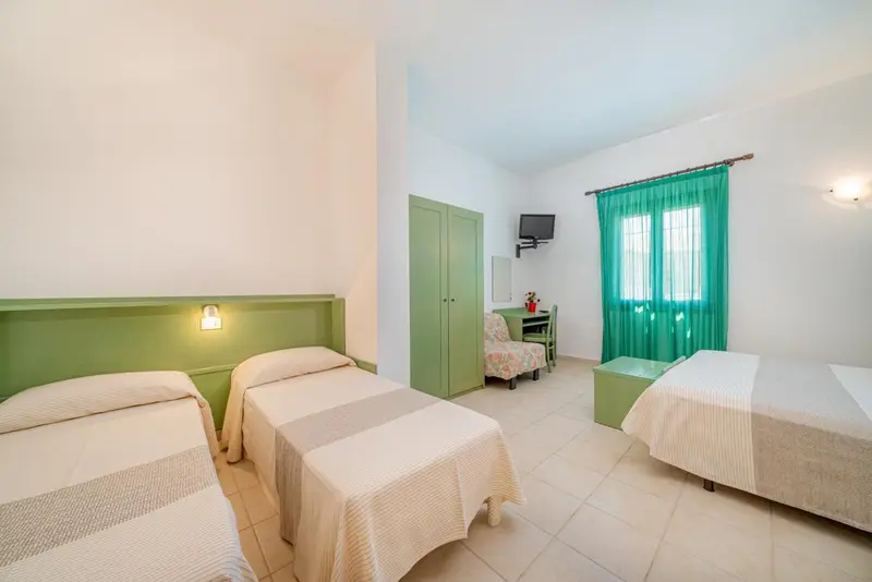 Une chambre lumineuse avec deux lits simples et un bureau près de la fenêtre.