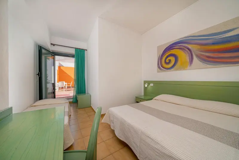 Chambre lumineuse avec un lit et un accès à une terrasse.