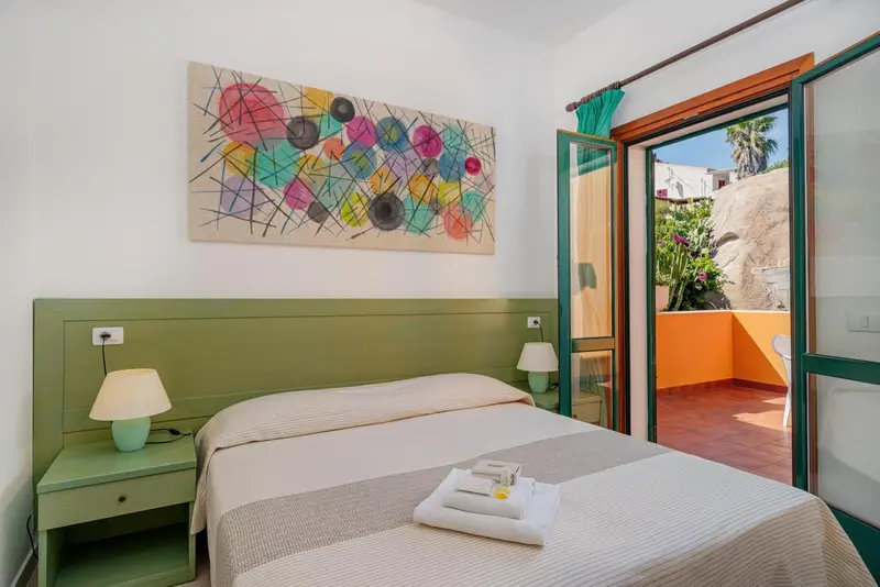 Une chambre lumineuse avec un lit et un accès à une terrasse.