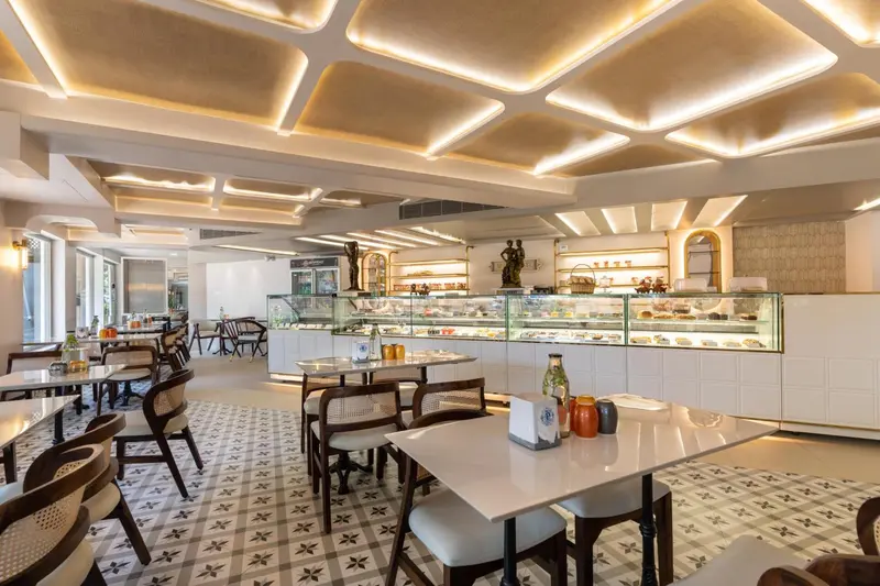 Une salle lumineuse avec des tables et des vitrines remplies de pâtisseries.