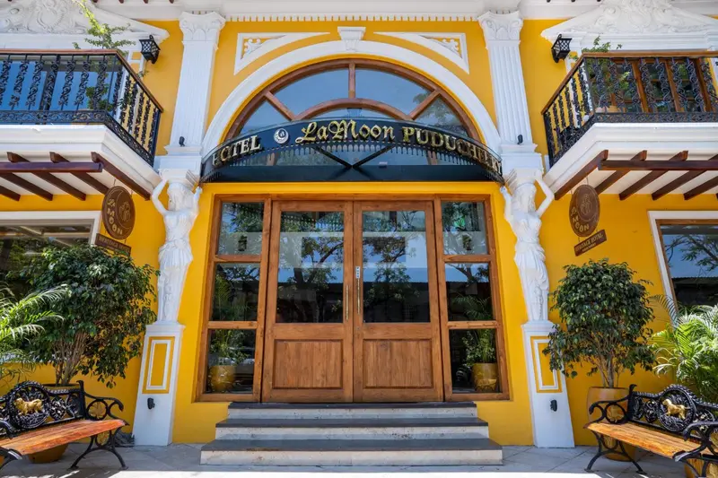 Facade jaune d'un bâtiment avec une arche et des bancs noirs.