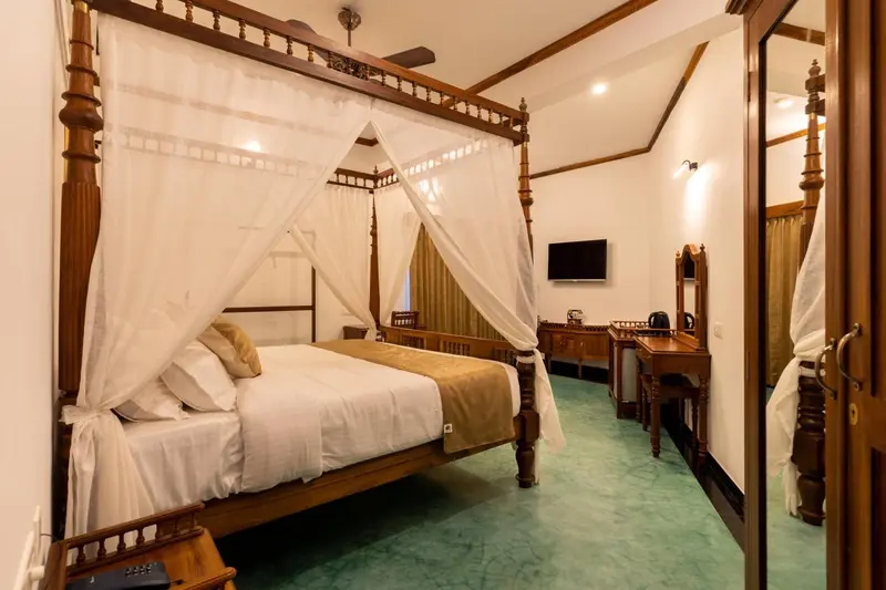 Une chambre avec un grand lit à baldaquin et un bureau en bois.