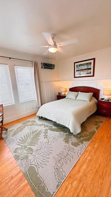 Une chambre lumineuse avec un lit recouvert d'une couverture blanche et un tapis à motifs.