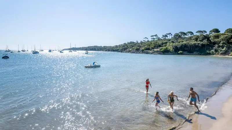 Des personnes s'amusent dans l'eau sur une plage ensoleillée.
