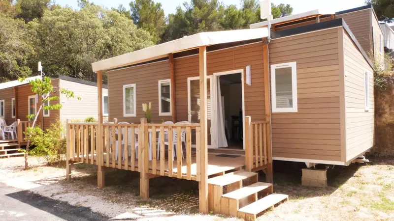 Mobil-home en bois avec terrasse et escaliers d'accès.