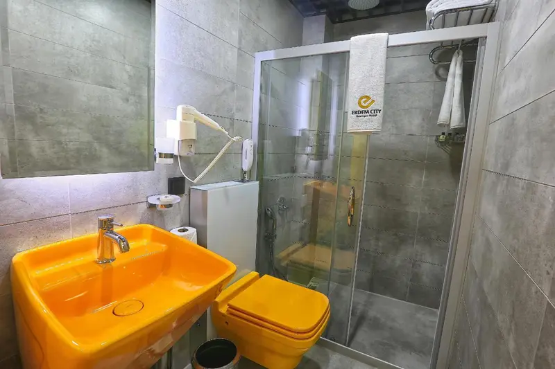 Une salle de bain moderne avec douche vitrée et lavabo jaune.