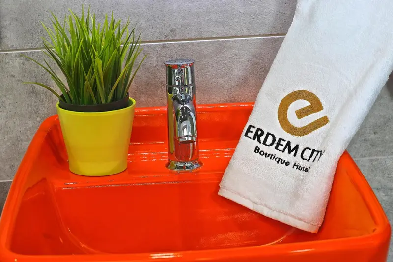 Un lavabo orange vif avec un robinet chromé et une serviette blanche.