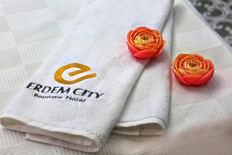 Serviette blanche brodee d'un logo et ornee de fleurs roses.