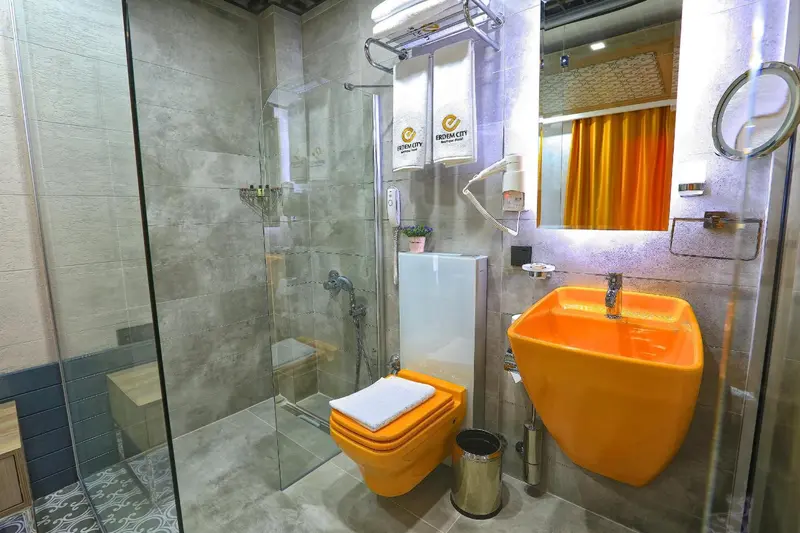 Une salle de bain moderne avec douche à l'italienne et lavabo orange.