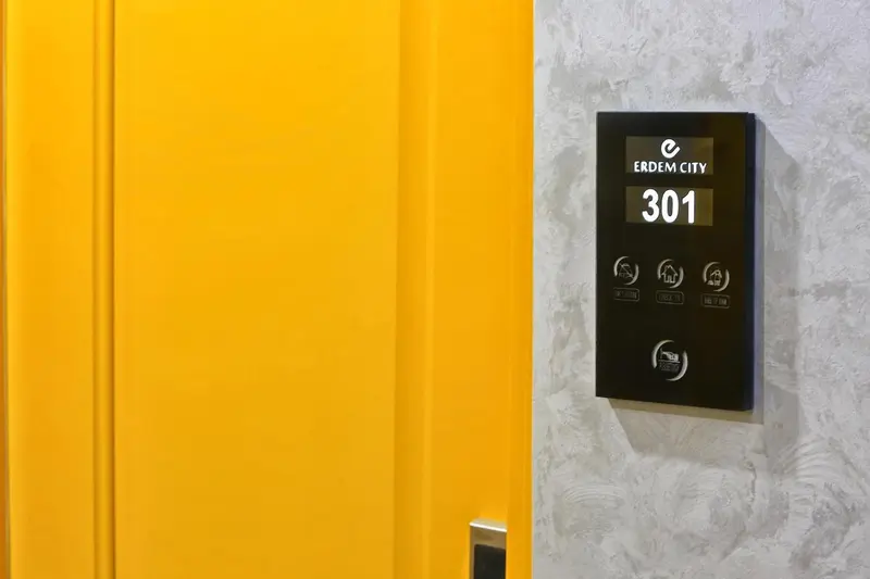 Porte jaune d'une chambre d'hôtel avec un panneau numérique.