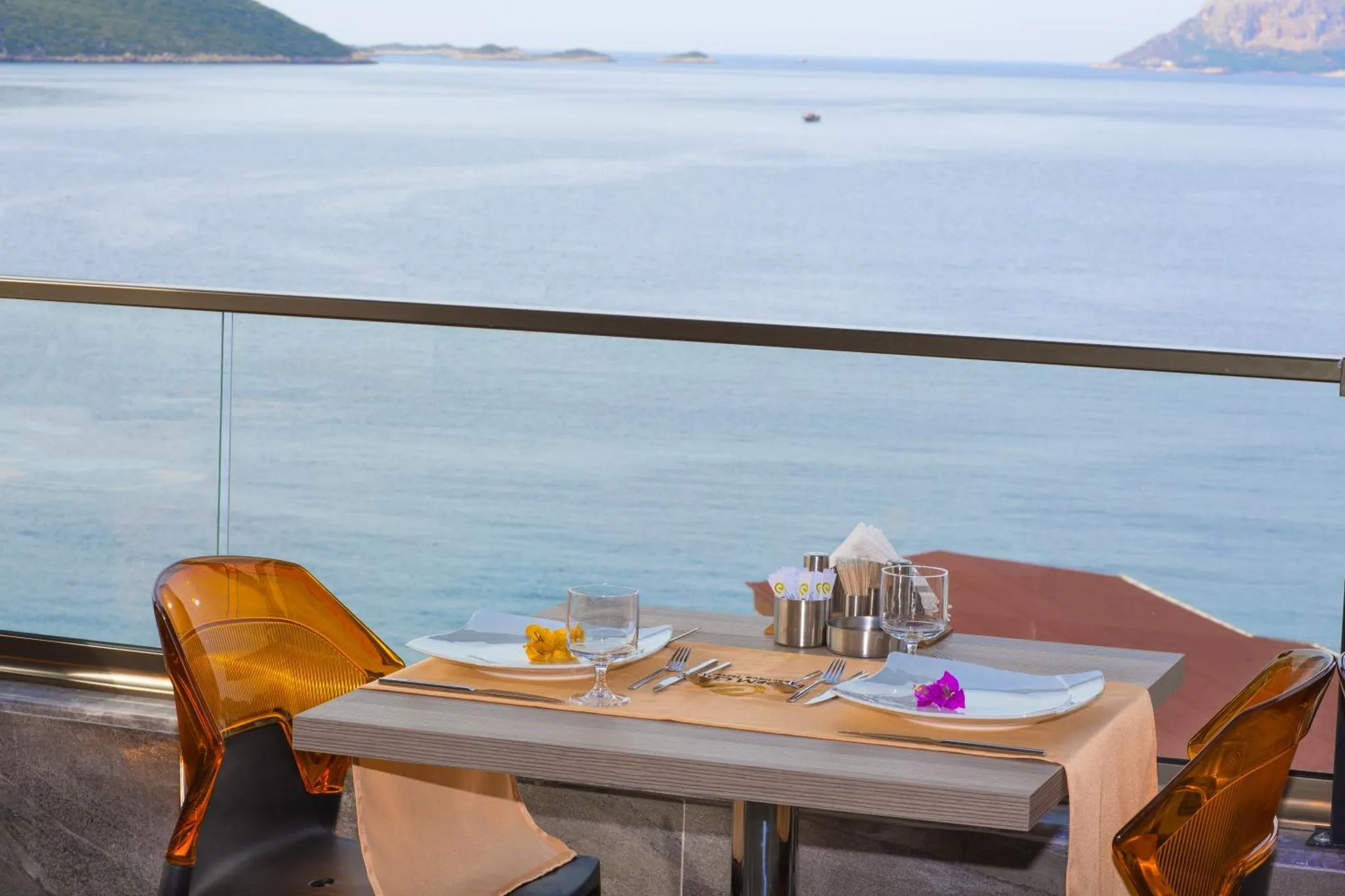 Une table est dressée sur une terrasse avec vue sur la mer.