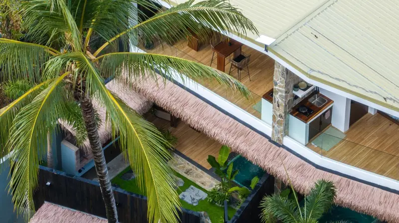 Terrasse en bois avec cuisine extérieure et végétation tropicale.