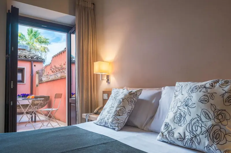 Une chambre lumineuse s'ouvre sur une terrasse avec vue sur la végétation.