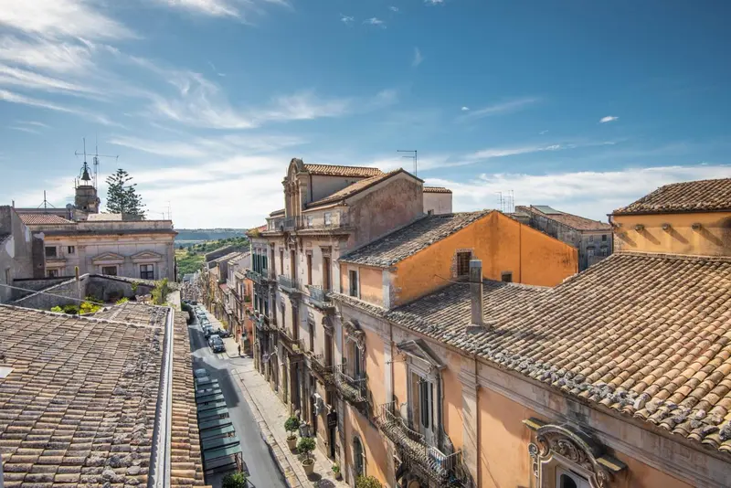 Vue aérienne sur les toits d'une ville historique avec des bâtiments aux façades claires et des tuiles orange.