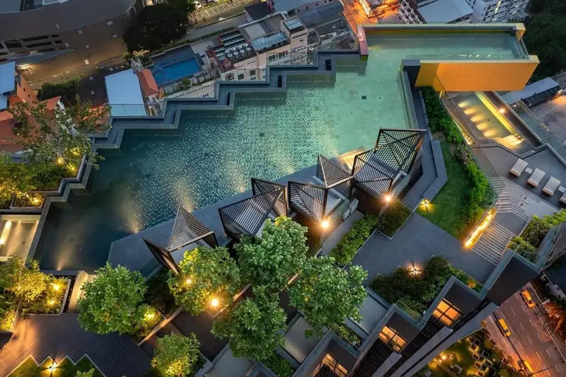 Vue aérienne d'une piscine sinueuse bordée de végétation et de structures géométriques.