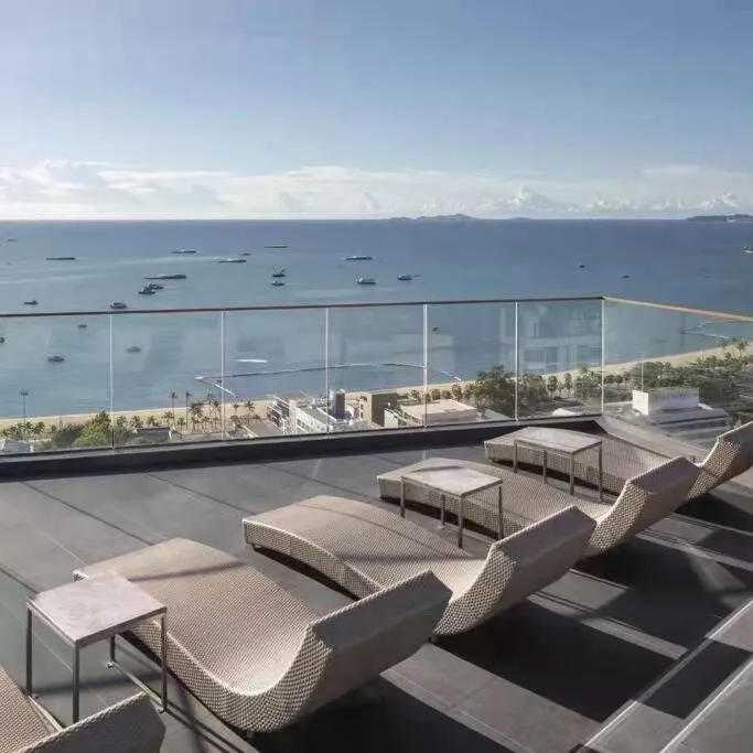 Transats et tables basses sur une terrasse avec vue sur la mer et la plage.