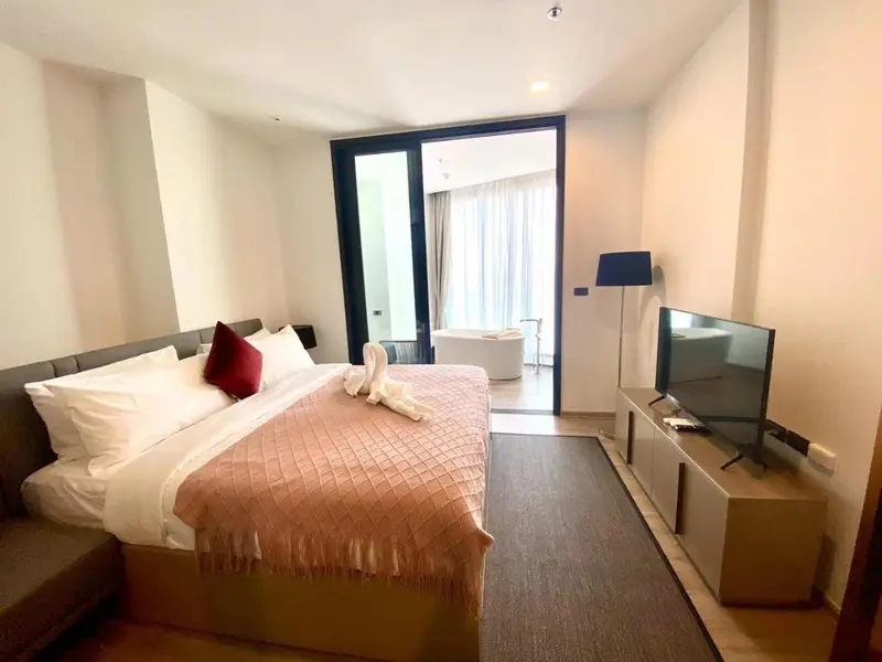 Chambre lumineuse avec un grand lit et un accès à une terrasse.