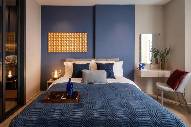 Une chambre moderne avec un grand lit recouvert d'une couverture bleue et des oreillers décoratifs.