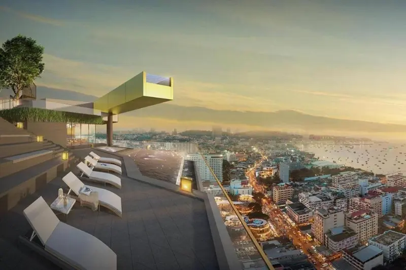 Terrasse avec transats et vue sur la ville au coucher du soleil.