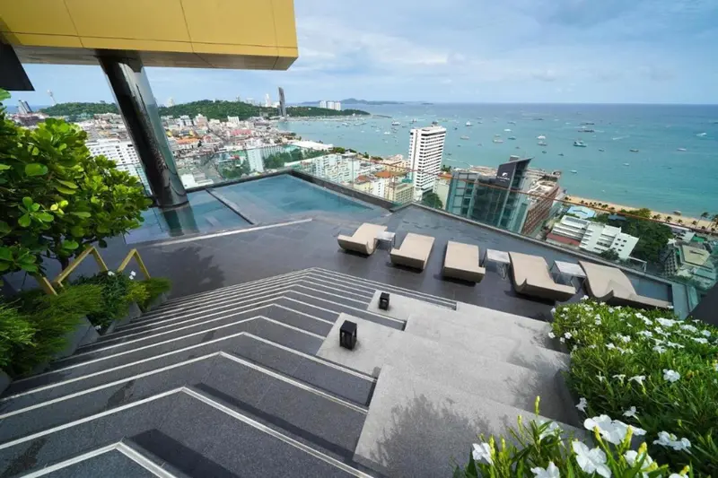 Terrasse avec transats surplombant une ville côtière et la mer.