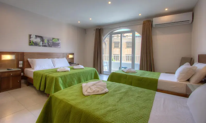 Une chambre lumineuse avec deux lits simples et un lit double.