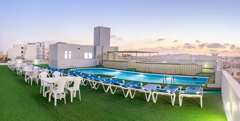 Terrasse avec piscine et chaises longues au coucher du soleil.