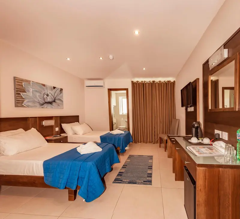 Une chambre d'hôtel lumineuse avec deux lits simples et un coin bureau.