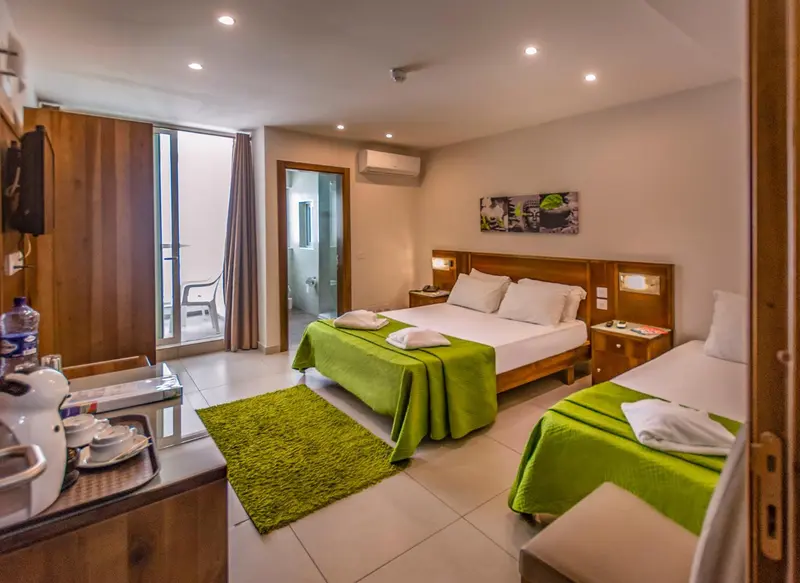 Chambre lumineuse avec un lit double et un lit simple, décorée de touches de vert.
