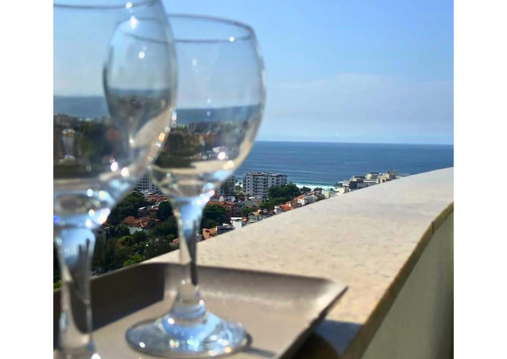 Deux verres à vin sur une table basse avec vue sur la mer et la côte.