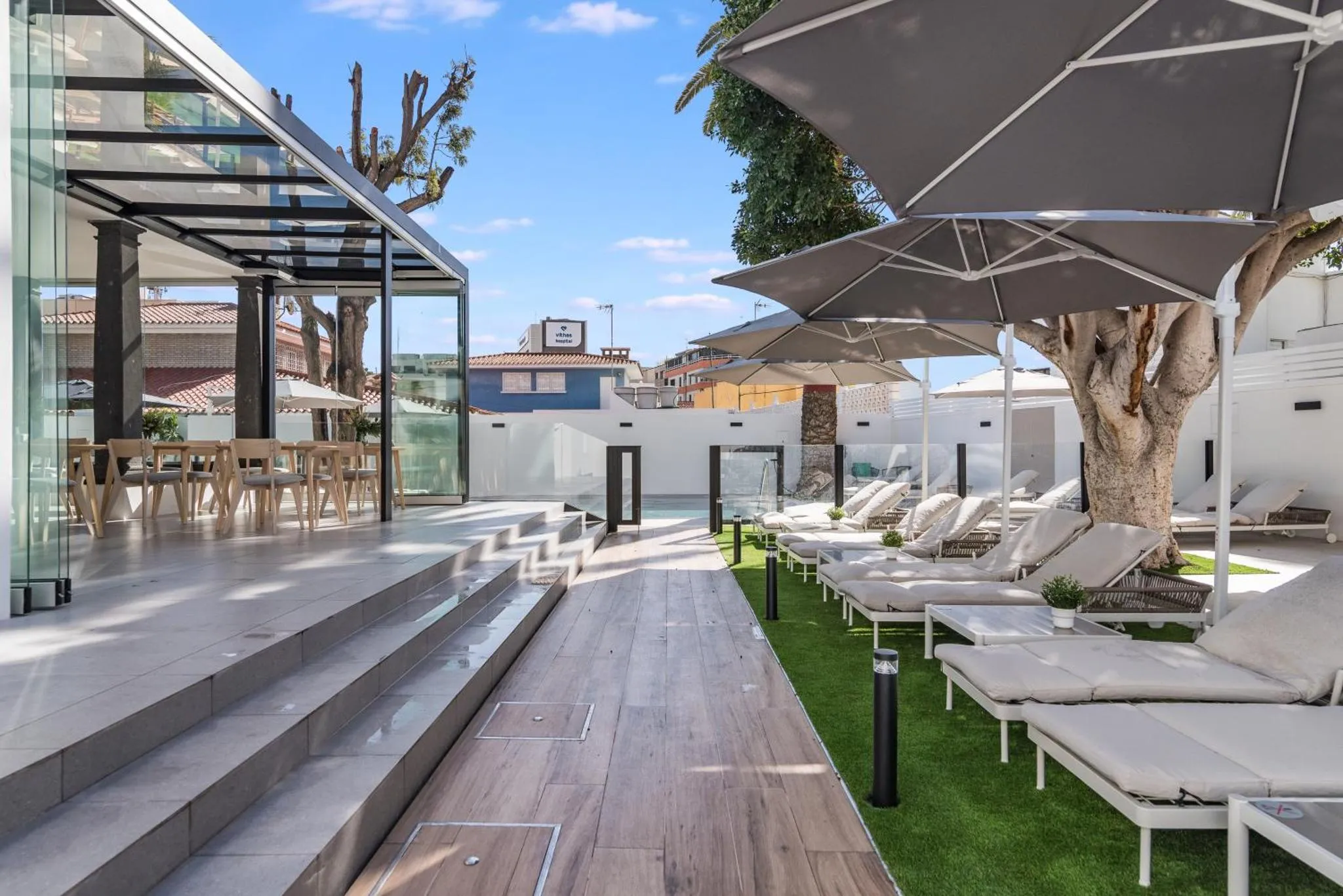 Terrasse aménagée avec transats et parasols près d'une piscine.