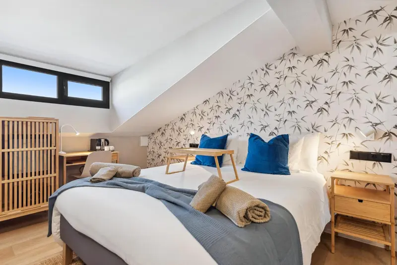 Une chambre lumineuse avec un lit double et un bureau en bois.