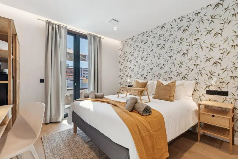 Une chambre lumineuse avec un grand lit et un accès à un balcon.