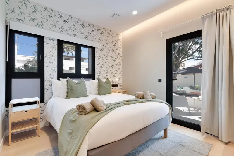 Une chambre lumineuse avec un grand lit recouvert d'une couette et de coussins verts.