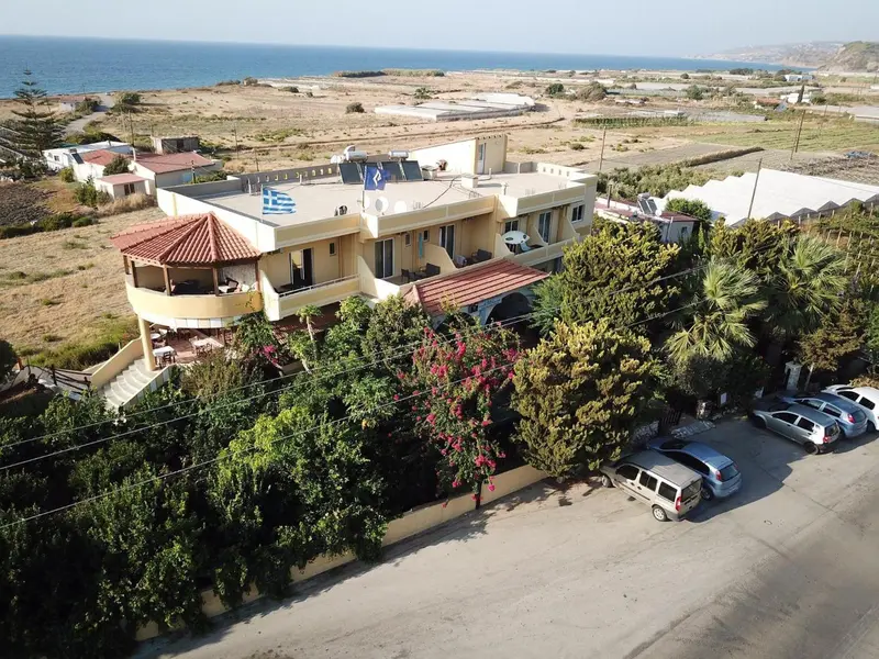 Bâtiment blanc avec toiture rouge et terrasse donnant sur la mer.