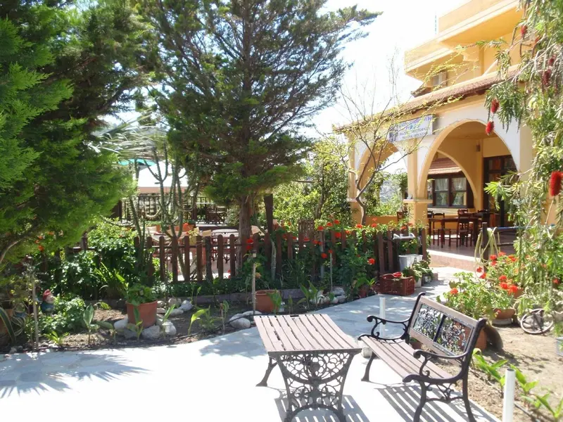 Un jardin fleuri avec un banc en fer forgé et une arche ombragée.