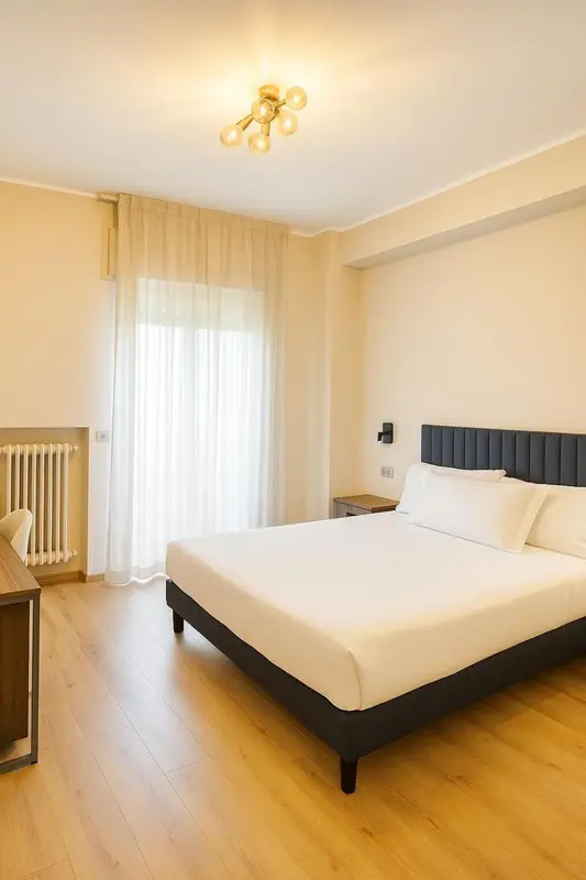 Une chambre lumineuse avec un grand lit et des rideaux clairs.