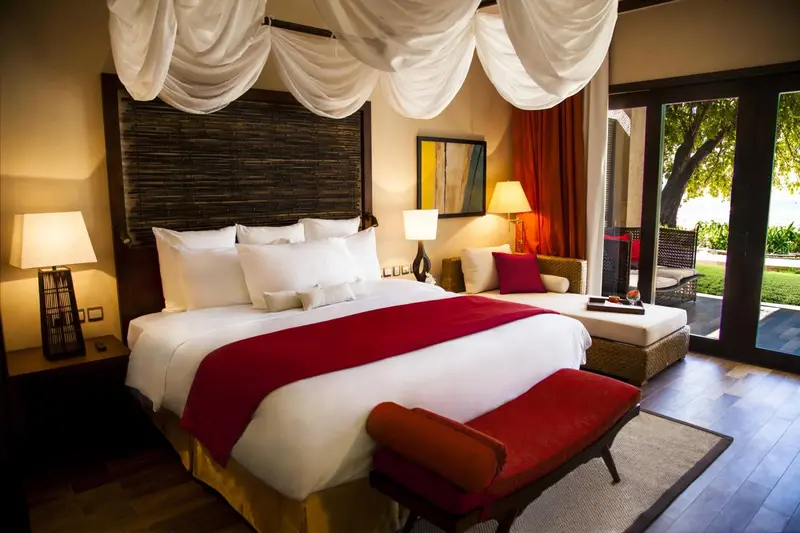 Une chambre avec un grand lit recouvert d'une courtepointe rouge et de coussins.